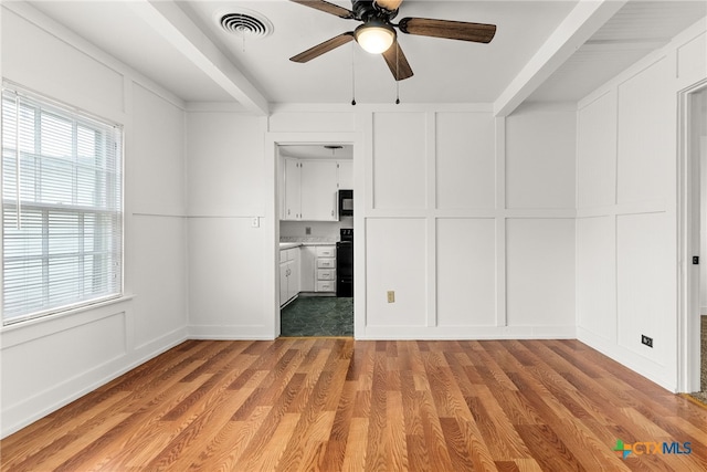 unfurnished bedroom featuring light wood-style floors, visible vents, and a decorative wall