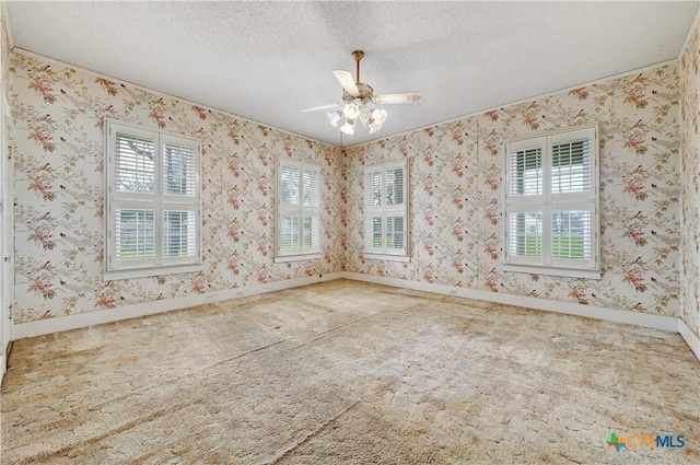 empty room featuring carpet floors, a textured ceiling, baseboards, and wallpapered walls