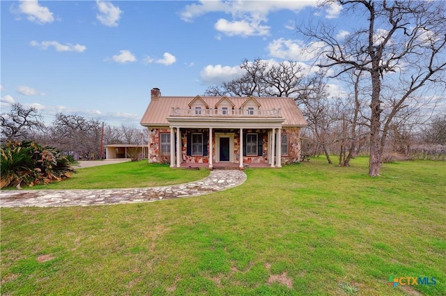 view of front of property with covered porch, a chimney, metal roof, and a front yard