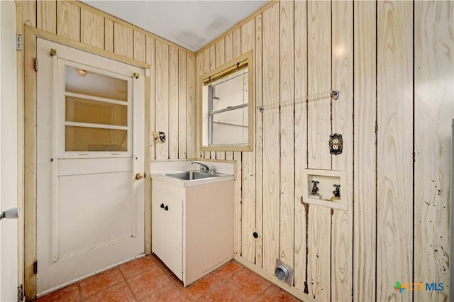 laundry area featuring light tile patterned floors, hookup for a washing machine, a sink, wood walls, and laundry area