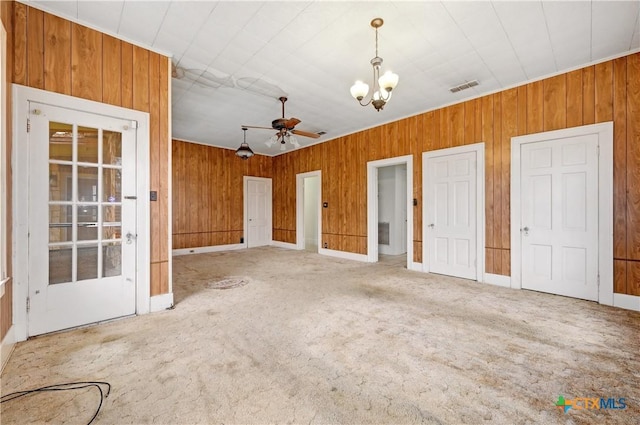 unfurnished bedroom featuring carpet floors, wood walls, visible vents, and a chandelier