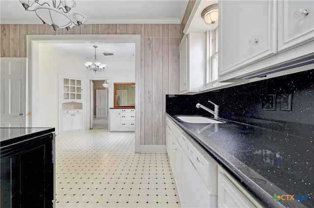 kitchen with light floors, ornamental molding, white dishwasher, a sink, and a chandelier