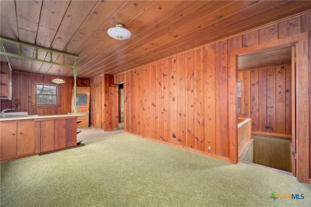 kitchen featuring carpet floors, wood walls, wood ceiling, and a sink