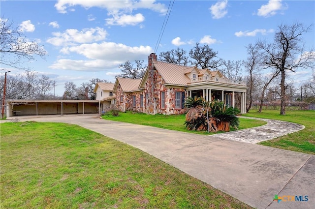 view of front facade featuring a chimney, metal roof, stone siding, driveway, and a front lawn