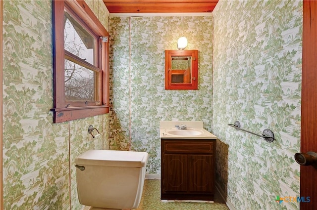 bathroom with vanity, toilet, and wallpapered walls