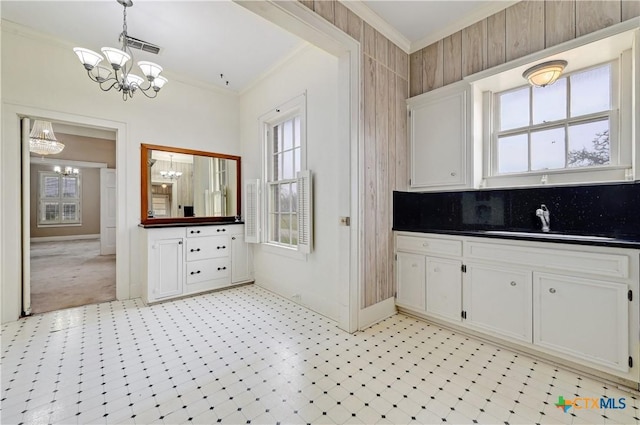 kitchen with dark countertops, an inviting chandelier, ornamental molding, and light floors