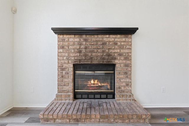 room details with wood-type flooring and a brick fireplace