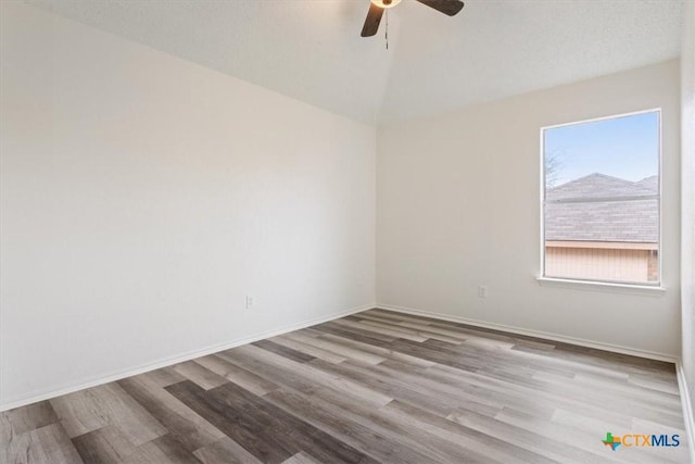 unfurnished room with a textured ceiling, light wood-type flooring, and ceiling fan