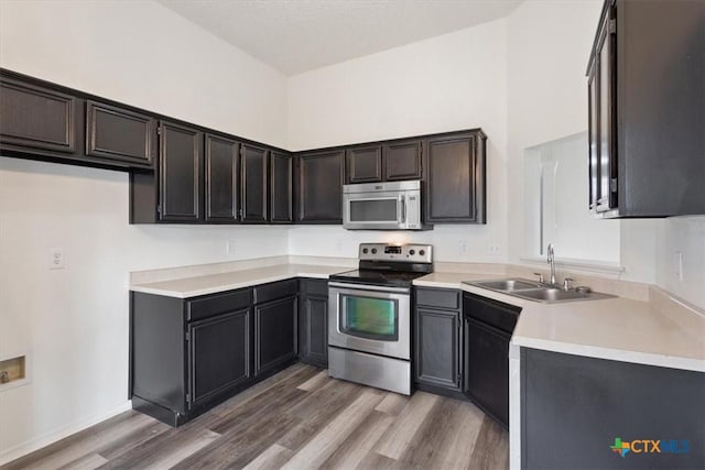 kitchen featuring sink, wood-type flooring, stainless steel appliances, and a high ceiling