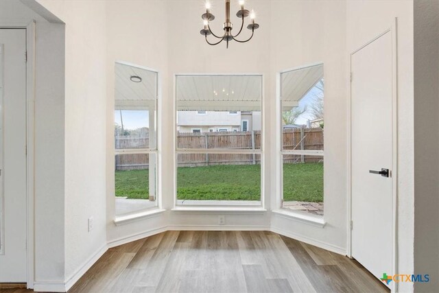 unfurnished dining area featuring a chandelier and light wood-type flooring