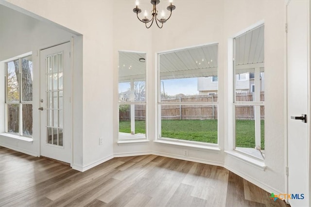 unfurnished dining area featuring plenty of natural light, wood-type flooring, and a chandelier