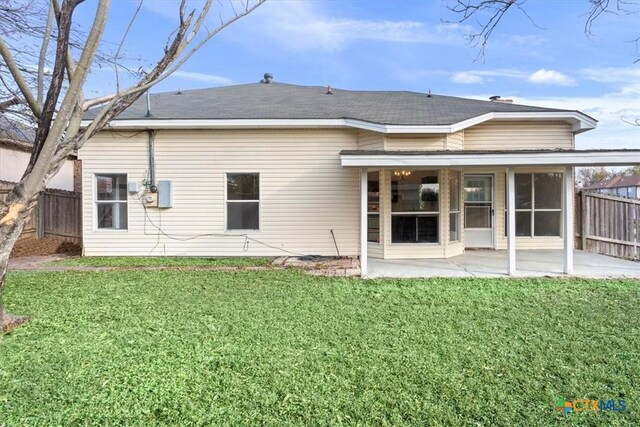 rear view of house featuring a yard, a patio, and a sunroom