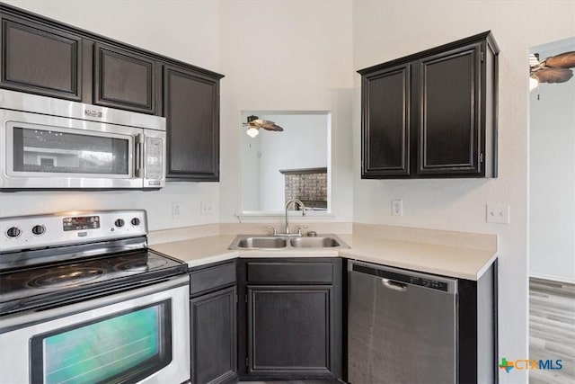 kitchen with hardwood / wood-style floors, ceiling fan, sink, and stainless steel appliances