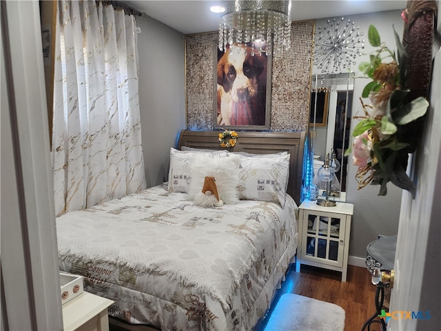 bedroom with dark hardwood / wood-style floors and a chandelier