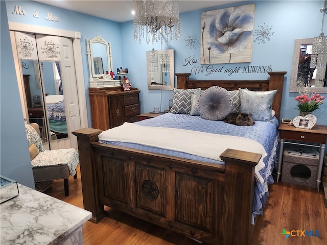 bedroom with wood-type flooring and an inviting chandelier