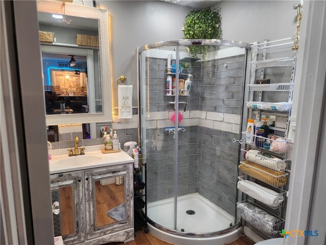 bathroom with hardwood / wood-style floors, vanity, and a shower with shower door