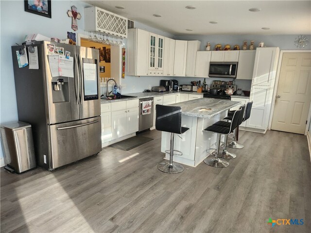 kitchen featuring stainless steel appliances, hardwood / wood-style flooring, sink, a kitchen breakfast bar, and a kitchen island