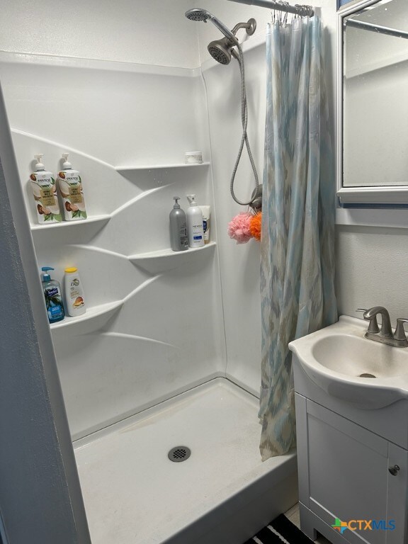 bathroom featuring walk in shower and vanity