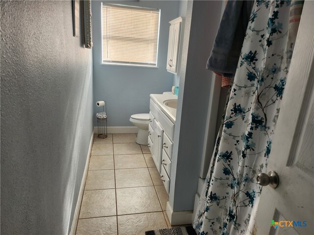 bathroom with curtained shower, vanity, tile patterned floors, and toilet