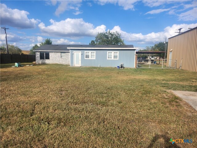 back of house featuring a lawn and a carport