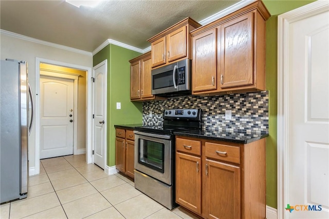 kitchen with stainless steel appliances, light tile patterned flooring, tasteful backsplash, brown cabinets, and ornamental molding