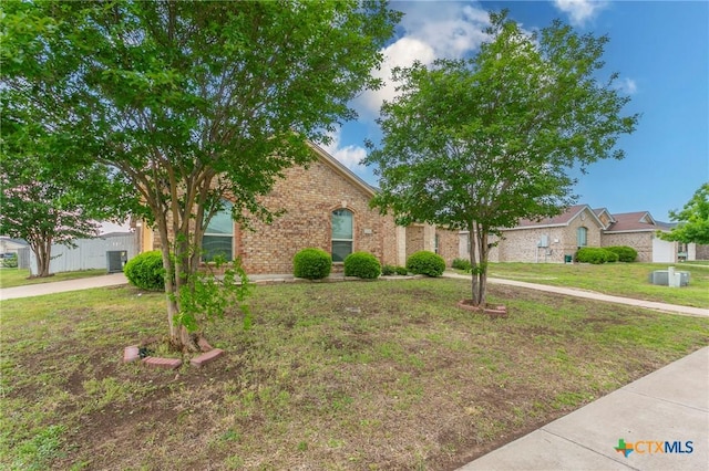 view of property hidden behind natural elements featuring brick siding and a front yard