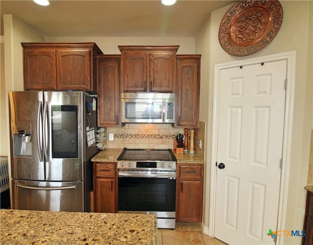 6704 Deorsam Loop, Killeen, TX 76542 - kitchen featuring appliances with stainless steel finishes, tasteful backsplash, light stone countertops, light tile patterned flooring, and recessed lighting