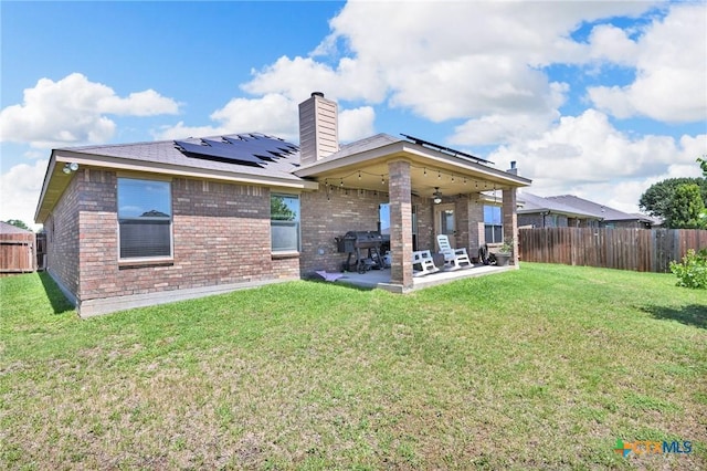6704 Deorsam Loop, Killeen, TX 76542 - rear view of house featuring a patio, roof mounted solar panels, brick siding, and a chimney
