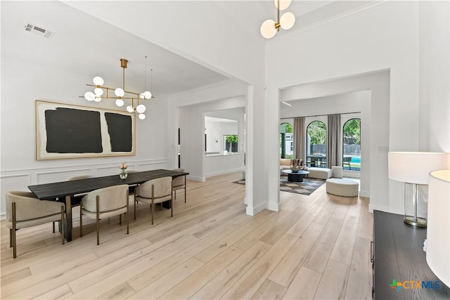 dining area with crown molding, light hardwood / wood-style flooring, and a chandelier