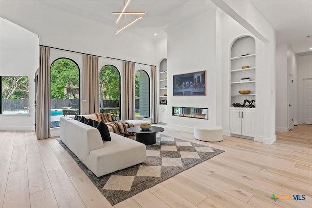 living room with built in shelves and light hardwood / wood-style flooring