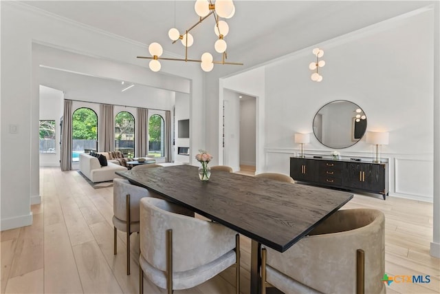 dining room featuring a notable chandelier, crown molding, light hardwood / wood-style flooring, and french doors