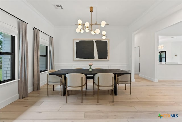 dining space featuring light wood-type flooring, ornamental molding, and an inviting chandelier