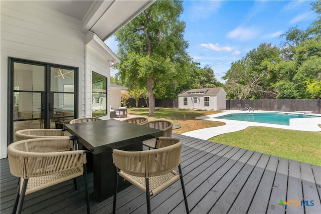 wooden deck featuring a fenced in pool, an outdoor structure, and a yard