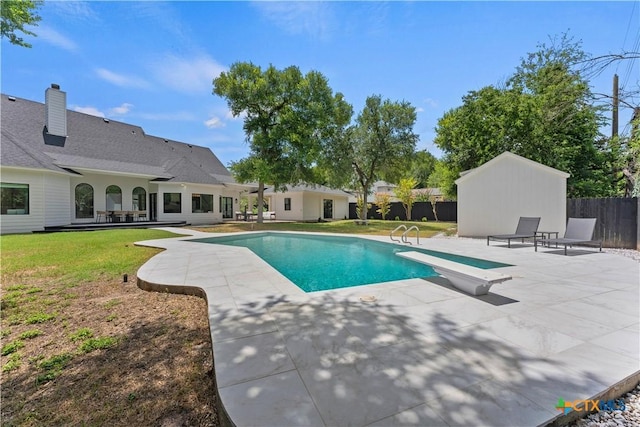 view of swimming pool with a yard, a diving board, and a patio area