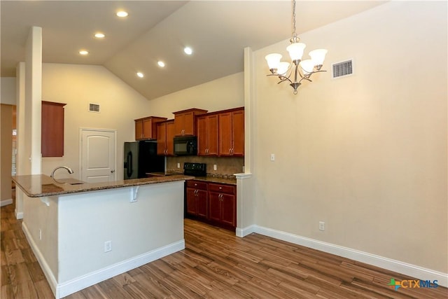 kitchen featuring dark stone counters, black appliances, decorative backsplash, kitchen peninsula, and a breakfast bar area