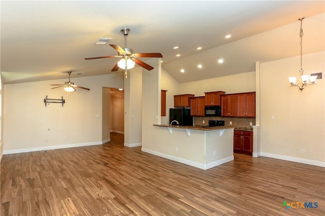 kitchen featuring a breakfast bar, decorative backsplash, hardwood / wood-style floors, and black appliances