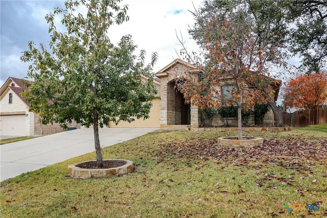 view of property hidden behind natural elements featuring a garage and a front lawn