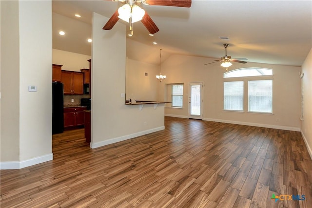 unfurnished living room featuring high vaulted ceiling, dark hardwood / wood-style floors, and ceiling fan with notable chandelier