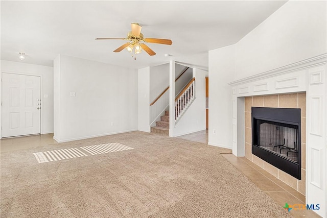 unfurnished living room with ceiling fan, light colored carpet, and a tile fireplace