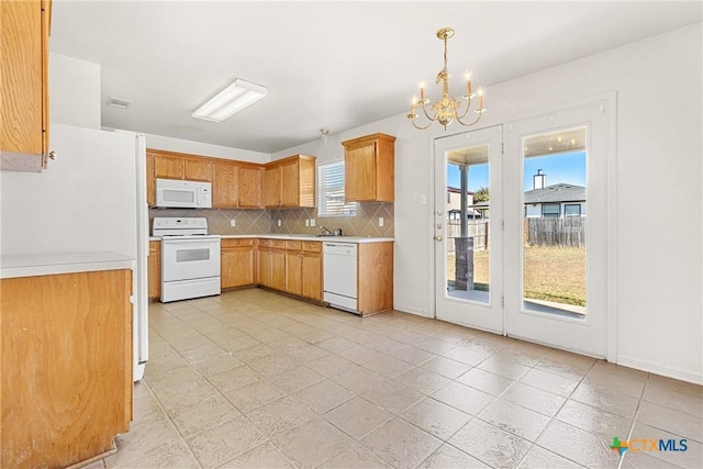 kitchen with backsplash, white appliances, light tile patterned floors, a notable chandelier, and hanging light fixtures