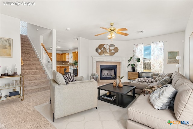 carpeted living room with ceiling fan and a fireplace