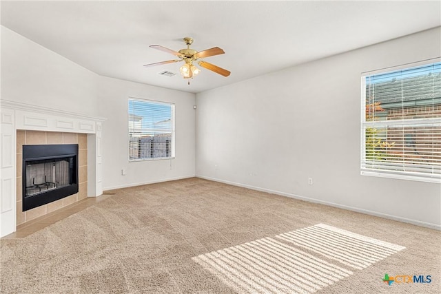 unfurnished living room featuring a tile fireplace, light carpet, and ceiling fan