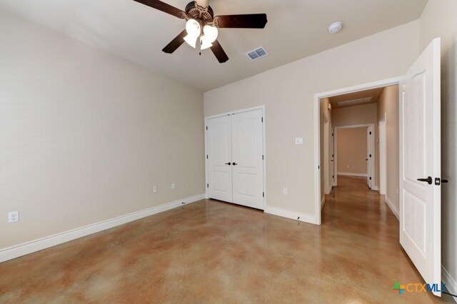 unfurnished bedroom with visible vents, concrete floors, ceiling fan, baseboards, and a closet