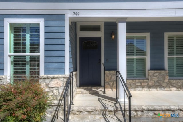 doorway to property featuring covered porch and stone siding