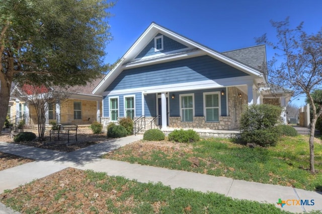 bungalow featuring stone siding and a porch