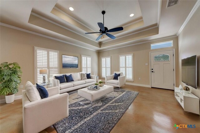 living area featuring visible vents, baseboards, ornamental molding, a raised ceiling, and a ceiling fan