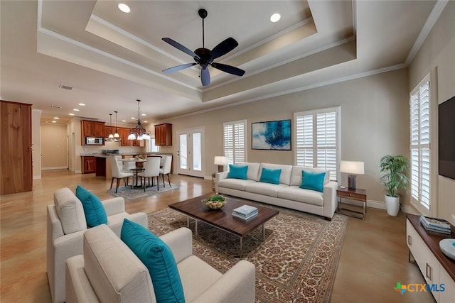 living room with a raised ceiling, crown molding, and a wealth of natural light