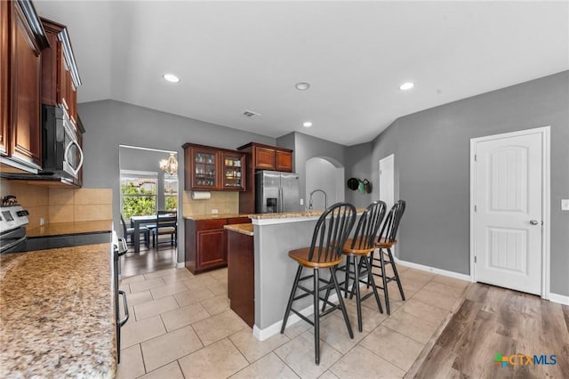 211 W Vega Ln, Killeen, TX 76542 - kitchen featuring appliances with stainless steel finishes, a kitchen breakfast bar, backsplash, recessed lighting, and glass insert cabinets
