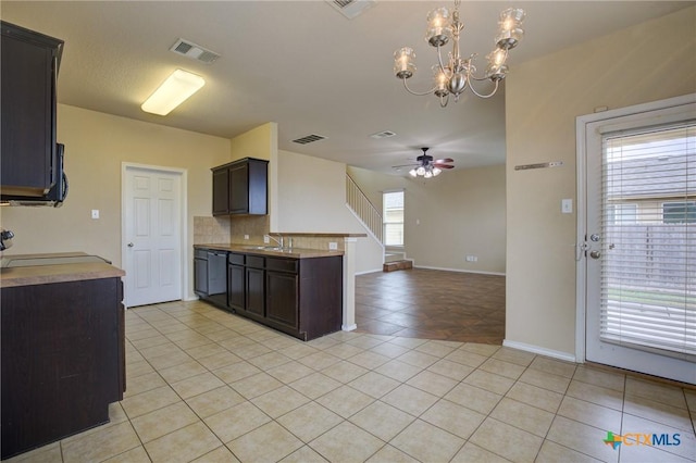 kitchen with a wealth of natural light, light tile patterned floors, and ceiling fan with notable chandelier