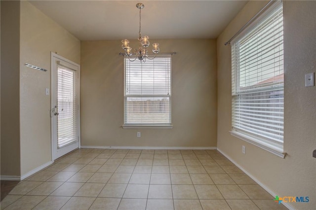 tiled empty room featuring a chandelier